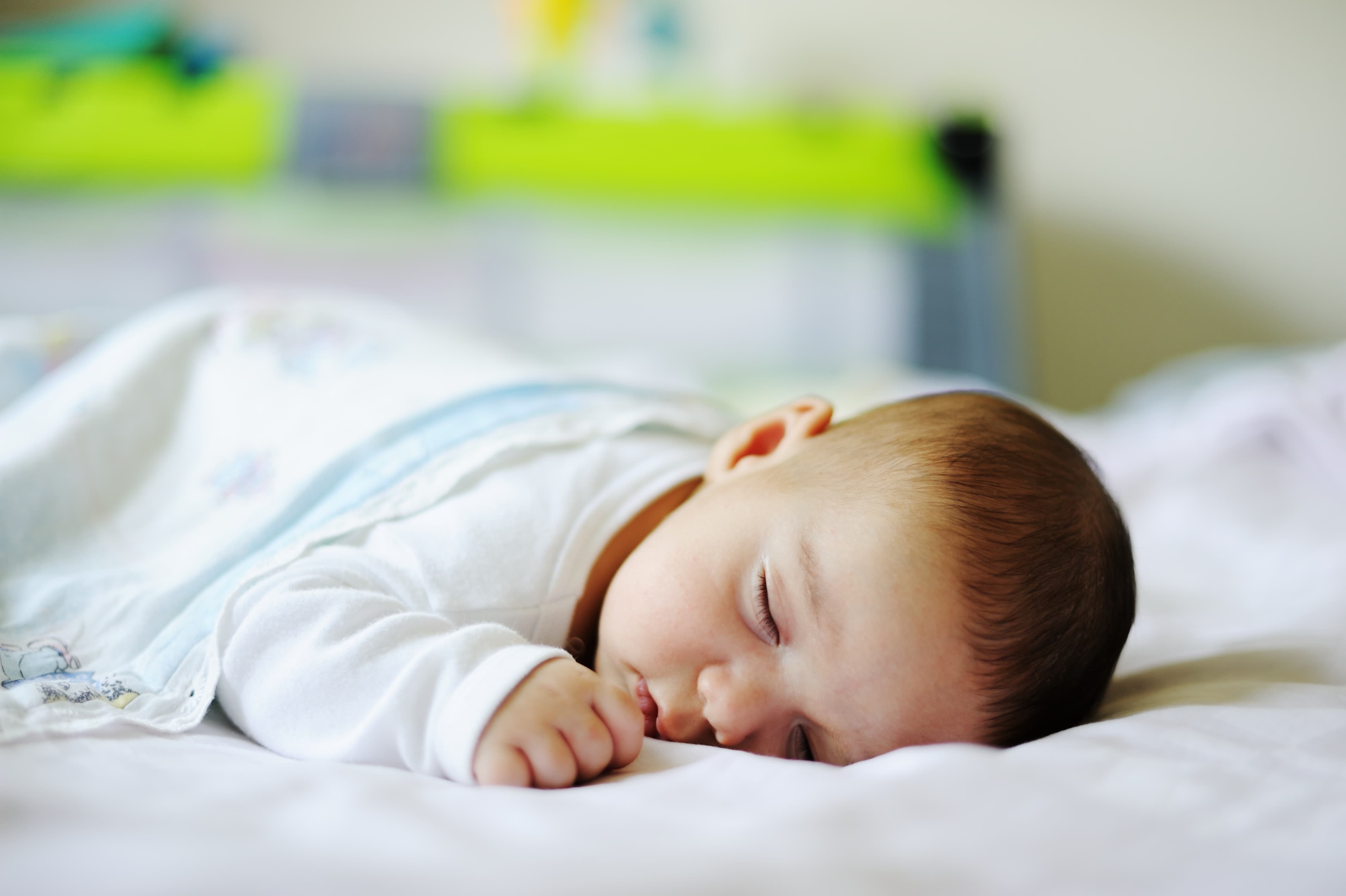 A peaceful sleeping baby on soft white bedding