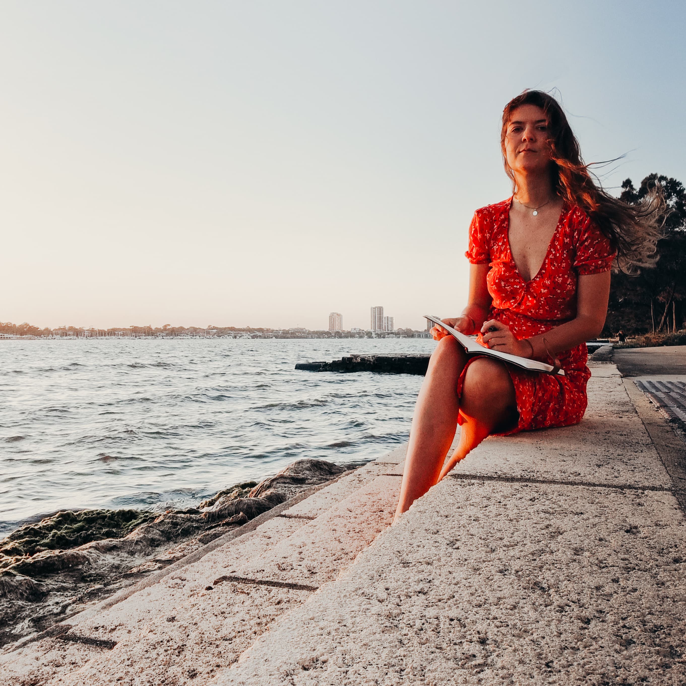 Holly Schroeder sitting by the water at sunset